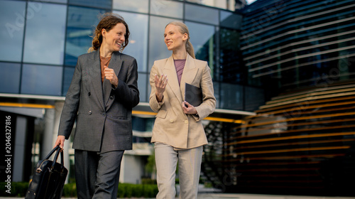 Two women walk and talk out...