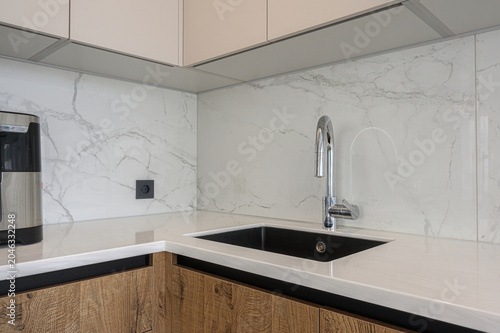 Photos Modern kitchen corner with white marble-patterned backsplash, sleek black underm