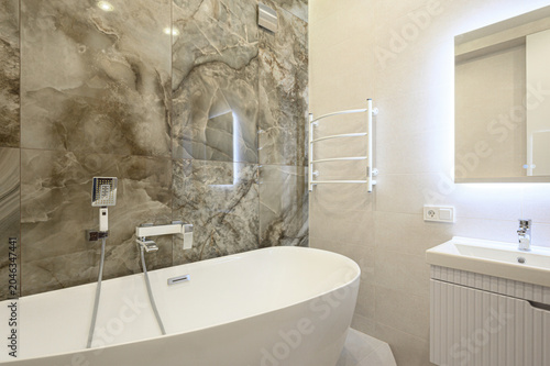 Schilderij op canvas Modern bathroom with freestanding white bathtub, large marble-effect tiles, LED-