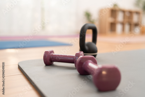 Weights and kettlebell resting on exercise mat in studio during workout session