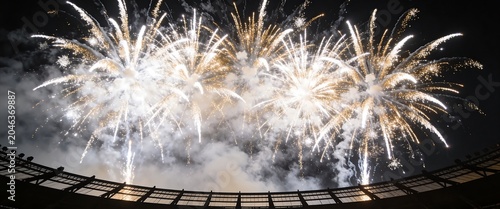 Spectacular golden and white fireworks display exploding over a stadium roof during a grand celebration