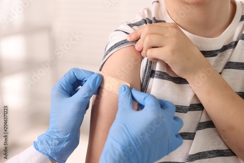 Obraz na płótnie Nurse in medical gloves applying adhesive bandage onto patient's arm after vacci