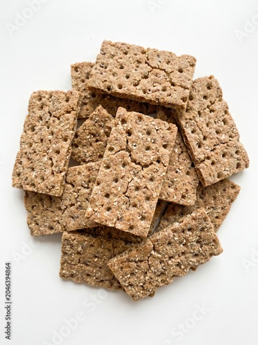 Stack of whole grain crispbread crackers isolated on white background. Healthy snack, dietary food and high fiber nutrition concept.