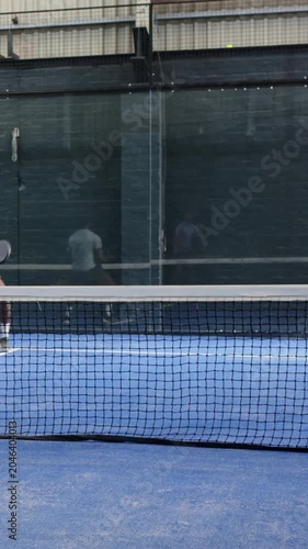 Vertical video: Lunging player in sportswear returning incoming ball on blue court with racket