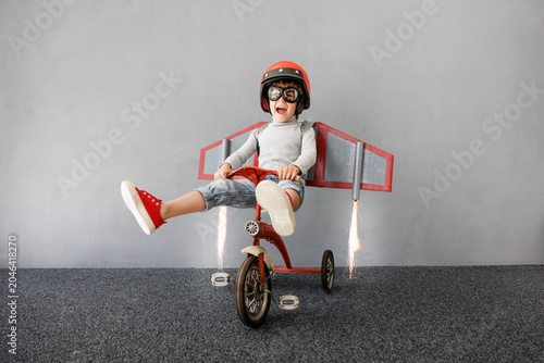 Happy child pretend to be astronaut. Funny kid with paper rocket. Little boy playing indoors