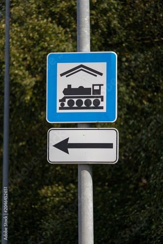 European road sign indicating train station direction, left arrow