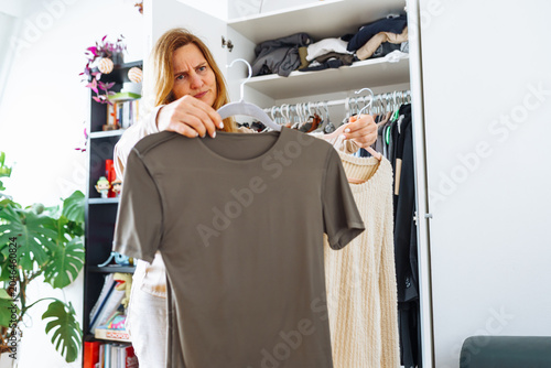 Obraz na płótnie middle-aged woman tries on clothes from her home wardrobe