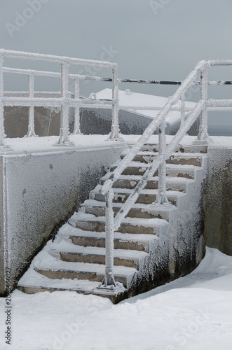 Concrete staircase with iron railings covered in snow during winter