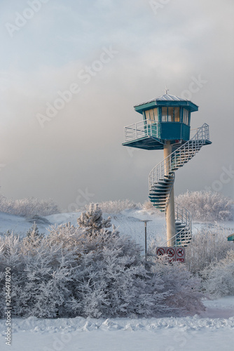 Snow-covered spiral lifeguard tower on a winter beach with dunes