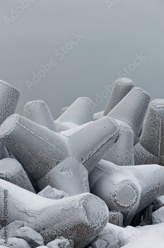 Frozen concrete breakwater elements on the winter shore