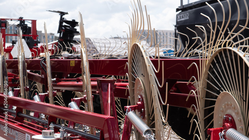 Cuadro en lienzo Close view of a red farm implement with multiple large metal wheels and curved t