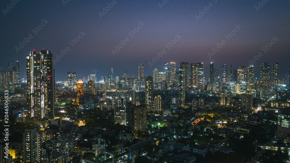 Fototapeta premium Cinematic aerial view of Mumbai city at night. Mumbai's iconic financial district with this stunning cityscape view—Shot of Mumbai Skyline, high-rise buildings in South Mumbai, Maharashtra, India.