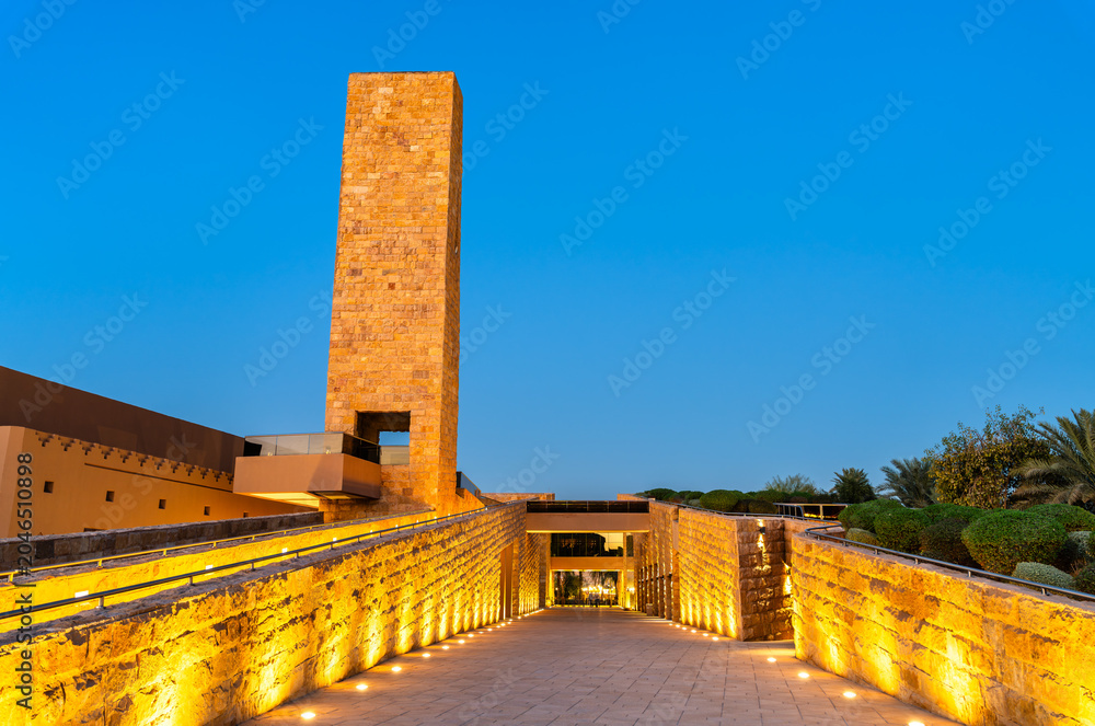 Obraz premium Sheikh Muhammad ibn Abd al-Wahhab Mosque with a beautifully illuminated stone tower and walkway in Diriyah, Riyadh, Saudi Arabia during blue hour