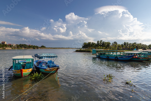 Tableau sur toile Traditional tourist boats moored on the Thu Bon River under a blue sky in Hoi An