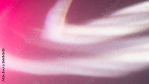 Abstract warm pink and purple light reflecting on textured wall creating soft shadows and bright glowing areas