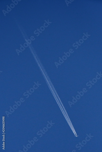 A two-engine jet with  three contrails. A drop in air pressure behind the fuselage and wings creates a third, invisible band of water vapor that condenses into a icy contrail 