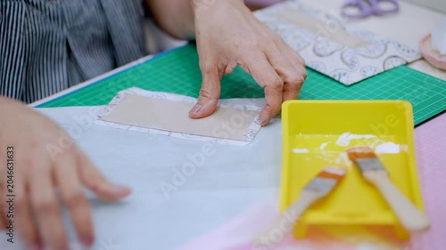 Close-Up Hands Applying Glue to Fabric and Template for Handmade Craft Project