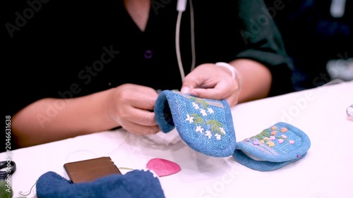 Craft artist sewing handmade leather wallet at workshop table