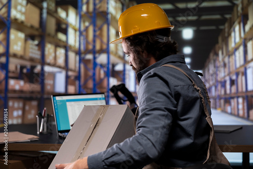 Photos Storehouse worker managing quality control on merchandise, scanning barcodes on depot boxes to create dispatch notes for inventory