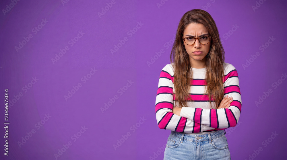 Obraz premium An angry woman with glasses and arms crossed, looking displeased with a frown