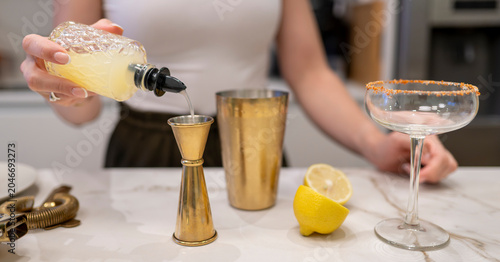 Obraz na płótnie Bartender pouring fresh citrus mix into gold jigger while preparing premium Marg