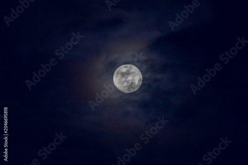 Super full moon in the night sky with clouds,