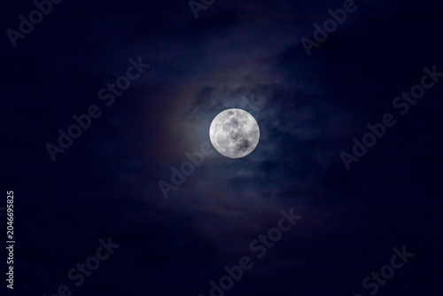 Super full moon in the night sky with clouds,