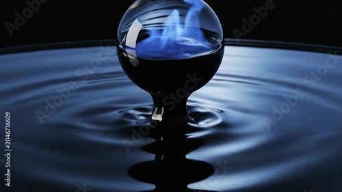 A glass orb containing fire floats on rippling water surface