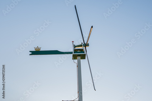 Tableau sur toile Vintage weather vane with crown symbol and wind propeller against clear blue sky