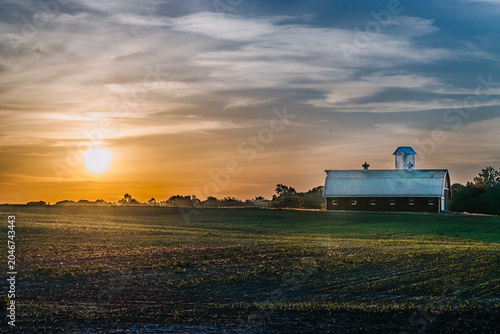 Sunrise over a barn in a field