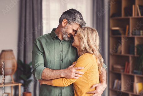 Tableau sur toile Happy Senior Caucasian Male And Female Embracing Each Other And Smiling At Home,
