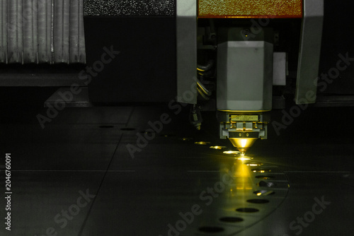 Tableau sur toile レーザー切断機が金属板に連続して穴をあけ黄色く発光する加工中の工作機械のクローズアップ