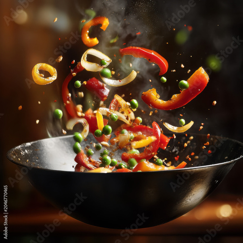 Colorful stir-fry vegetables in motion with steam in wok for asian restaurants and culinary schools concept of