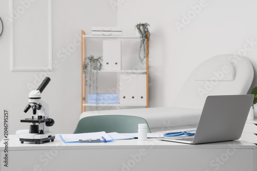 Doctor's desk with laptop and microscope in medical office