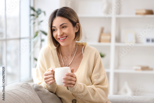 Attractive young woman with short hair drinking tea at home