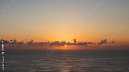 Golden sunset over tranquil ocean waves with soft cloud reflections at dusk