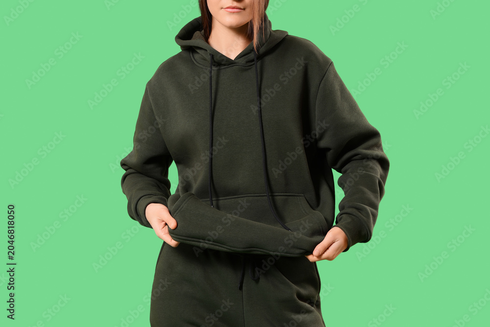 Fototapeta premium Young woman in sports suit on green background