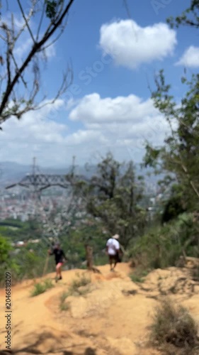 Two people hiking on mountain trail with city panoramic view below