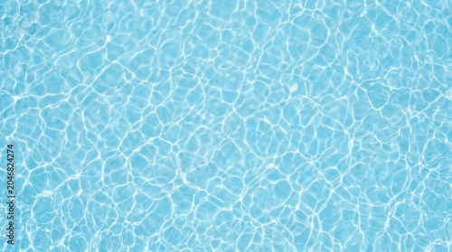 Top down view of crystal clear light blue water surface with gentle ripples and beautiful caustic light reflections