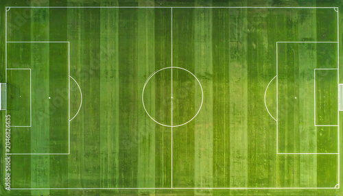 Aerial drone view of a vibrant green soccer field with white markings, showing goal areas and center circle, perfect for sports concepts