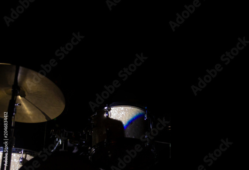 Minimal jazz drum kit in dark stage environment with large copy space, Minimal composition featuring a jazz drum kit partially illuminated on a dark concert stage. Strong negative space and low light 