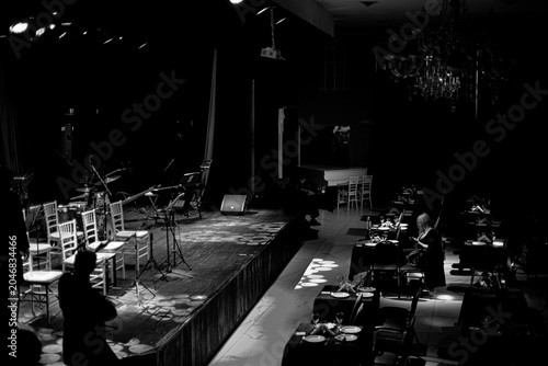 Empty jazz stage with chairs and instruments before performance in black and white with copy space, Black and white photograph of an empty jazz stage prepared for a live performance. Chairs