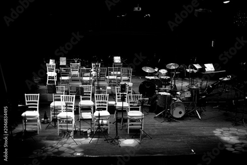 Empty jazz stage with chairs and instruments before performance in black and white with copy space, Black and white photograph of an empty jazz stage prepared for a live performance. Chairs