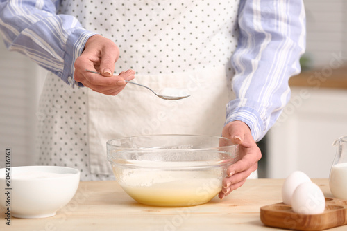 Woman putting spoon of suga...
