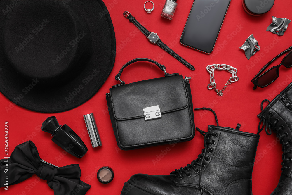 Obraz premium Composition with shoes, black hat, cosmetics and accessories on red background. Closeup