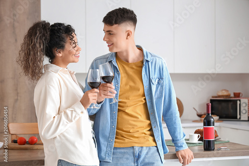 Happy young couple with glasses of wine at home