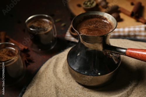 Pot with coffee in sand and...