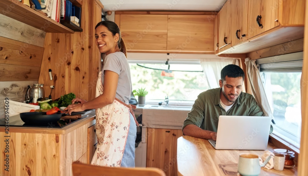 Obraz premium Couple enjoying life in a cozy camper van kitchen, cooking and working remotely.