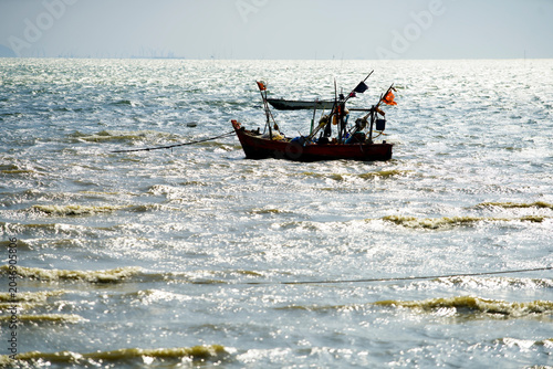 Traditional small fishing boat navigating in ocean waves during daytime