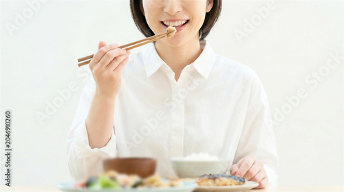 Happy young woman eating healthy home cooked meal at dining table
